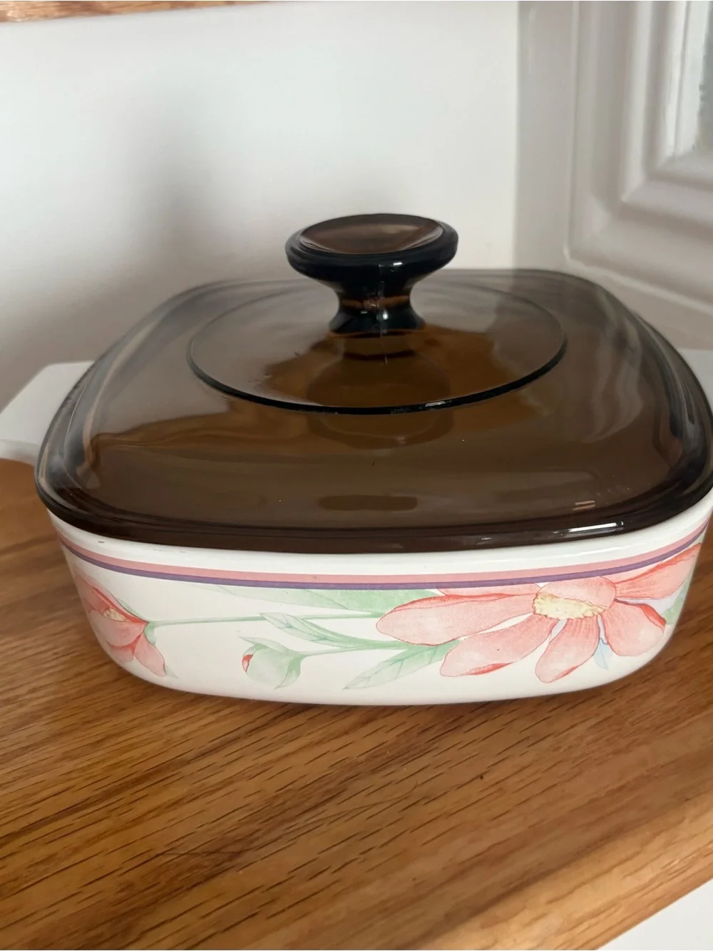 A vintage Corning Ware casserole dish in the Peony Floral pattern with lid